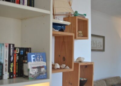 Shelves with books, some about the local area; other shelves hold seaside ornaments.