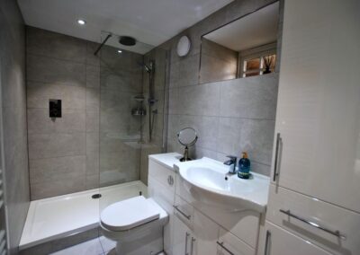 Tiled bathroom with walk-in shower and white bathroom suite.