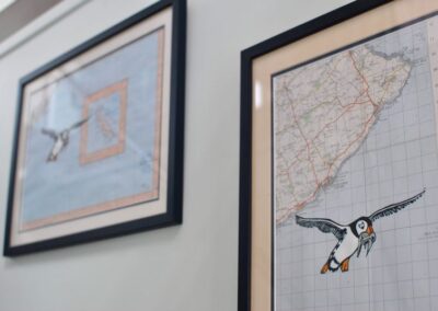 Framed maps of the East Neuk. Each has a print of a puffin over it.