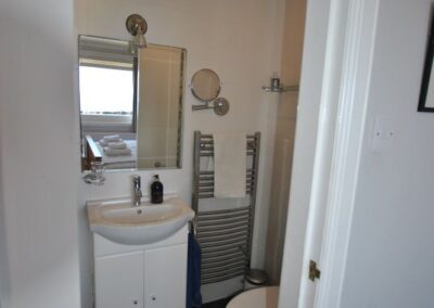 View from the door into the en-suite shower room. We can see the toilet, sink and a heated towel rail.