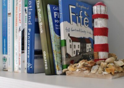 Books about Fife and Scotland, propped up with a red and white striped lighthouse design bookend.