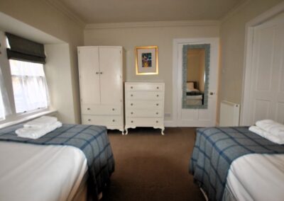 Single beds opposite white wardrobe and chest of drawers