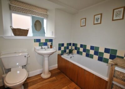 White suite with green, white and blue tiles around the bath and sink