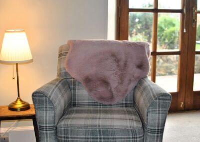 Armchair with pink fleece next to table and lamp.