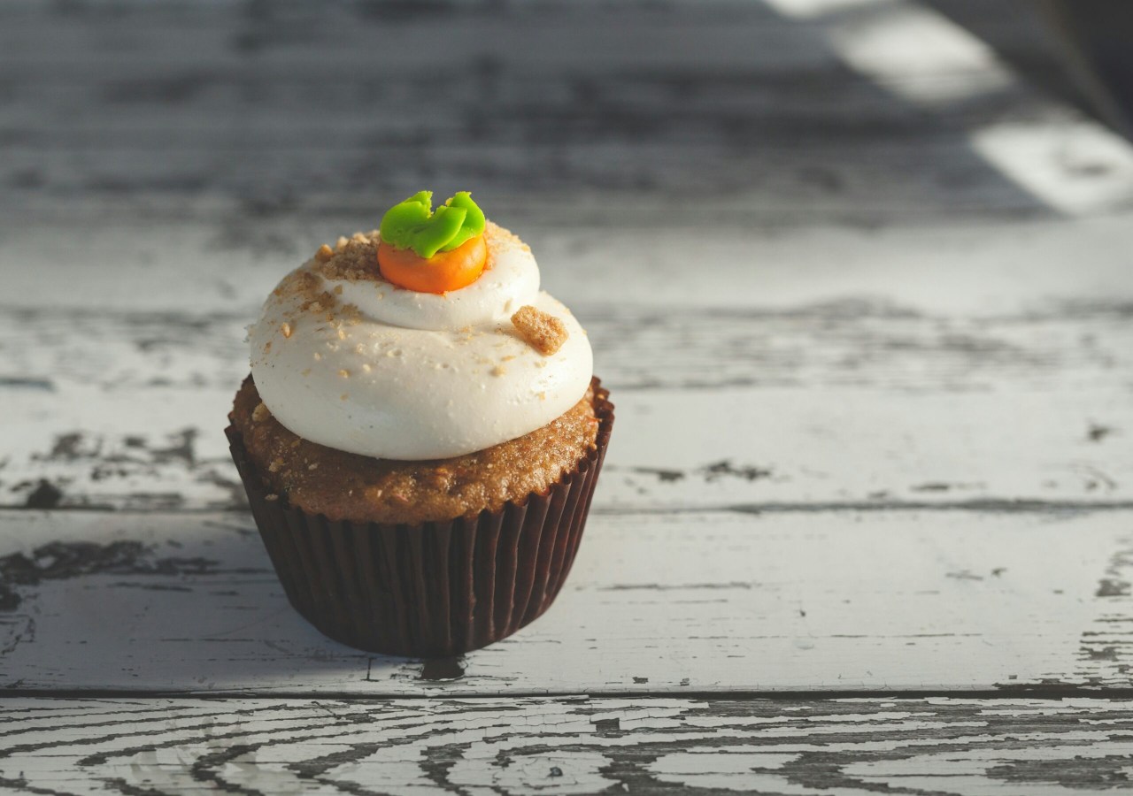 Cup cake topped with icing and what looks like a little carrot