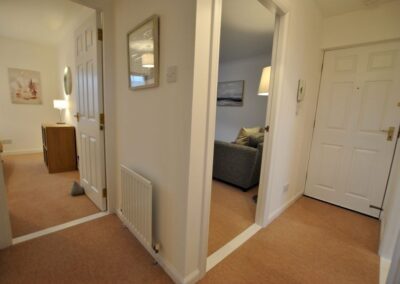 Hallway with front door, and two open doors through to lounge and bedroom.