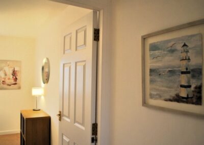 Framed painting of a lighthouse with seagull next to an open door.
