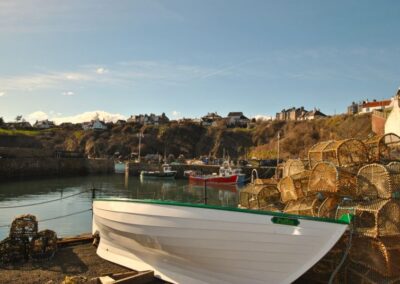 Boat and lobster creels in the foreground, before the harbour beyond.