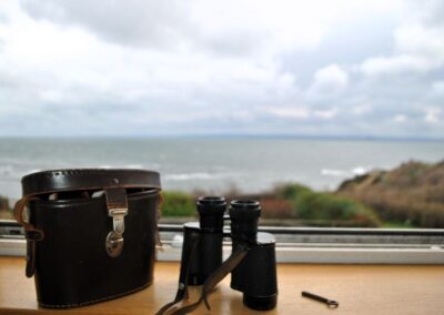 Binoculars on window ledge, looking out towards the sea.