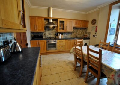 Kitchen cabinets on left and in front, with tiled floor and dining table with six chairs.