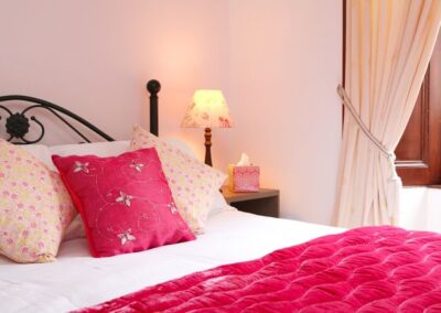 Pink and white bedding with wooden shutters in the background.