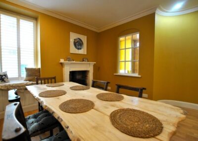 Long wooden dining table in a large room painted orange.
