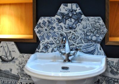 White sink basin with mixer tab surrounded by Delft blue-like tiling.