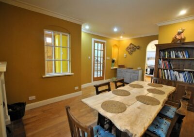 View across yellow and orange themed dining room into the kitchen beyond.