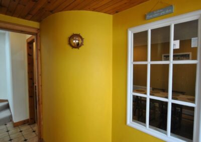 Curved yellow wall next to a nine-pane window.
