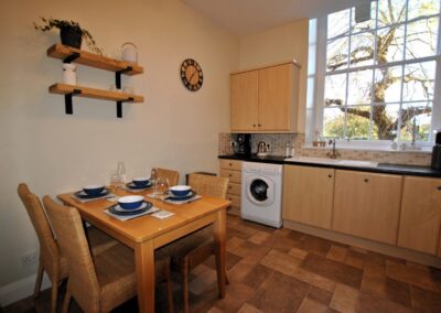 Kitchen table set for four within ample kitchen with large multi-paned window.