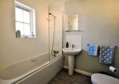White bathroom suite with shower above bath.