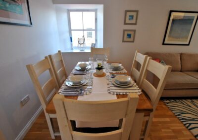 Table set for six with lounge on the right and a window at the head of the table.