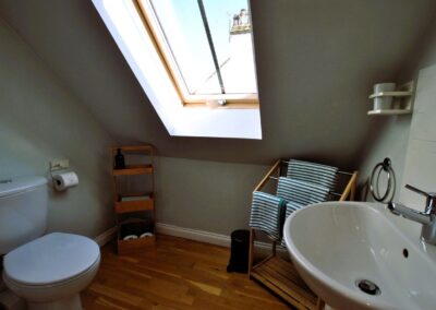 White bathroom suite beneath sloped roof with skylight window.