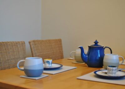 Blue teapot and cups on table.