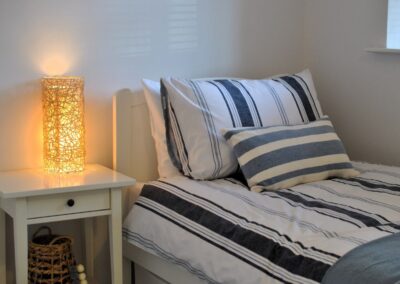 Bed with blue and white stripped covers next to bedside table with lamp.
