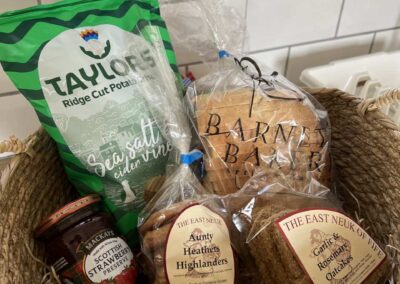 Basket with jam, biscuits, oat cakes, crisps and a loaf of bread