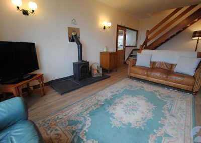 View of lounge across a Chinese rug towards a tan leather sofa and stairs curving to the right.