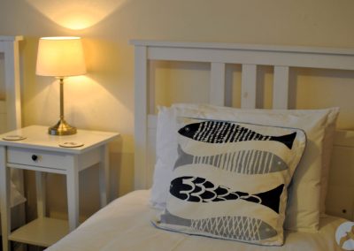 Pillow with fish design on white bed.