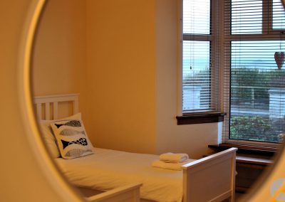 Reflection of single bed in round window.
