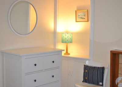 White chest of drawers beneath round window.