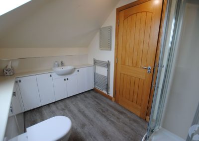 Heated towl rail and white bathroom basin behind door.