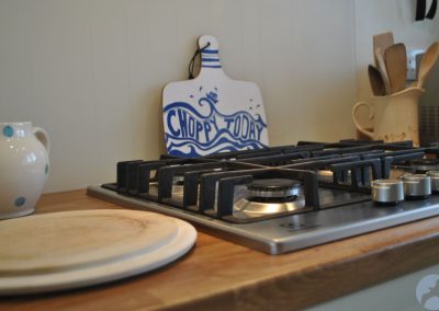 Close-up of gas hob with chopping board beneath with a sea design that reads Choppy Today.
