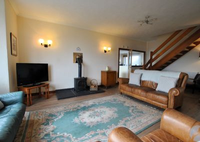 Wide view of lounge with plenty of seating and a large television.