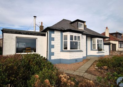 The house has paving, gravel and flowers in front.