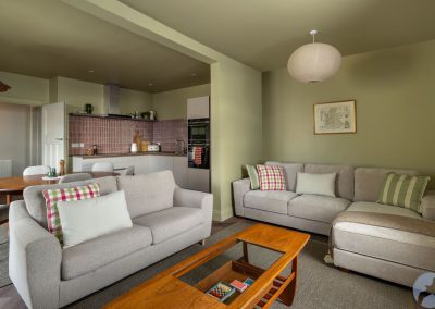 L-shaped sofa adjacent to another sofa with a kitchen and dining area behind.