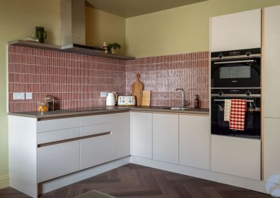 L-shaped kitchen with red and white striped tiles.