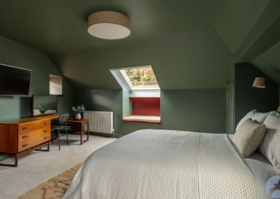 Double bed beneath a coved ceiling. There is a window set in the roof beyond.