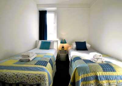 Two single beds with piles of towels on them.