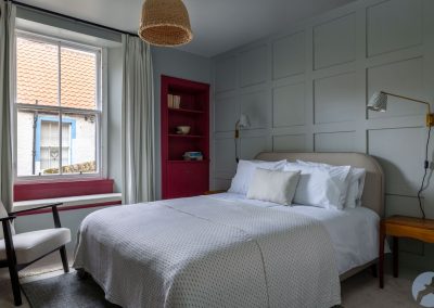 Double bed set against a panelled wall. There is a window to the left.