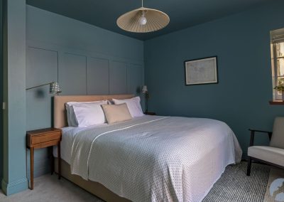 Double bed against a painted, panelled wall.