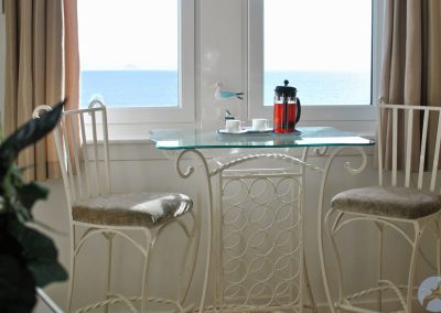 Metal chairs and table with a glass top in front of a window.
