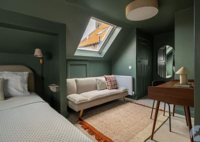 View across bed towards a sofa beneath a Velux-style roof window.