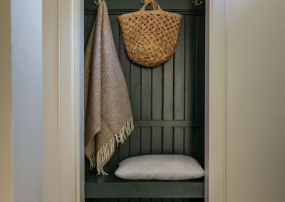In an alcoved seat hangs a shawl, picnic basket and beneath sits a picnic basket.