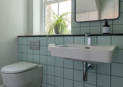 Tiled walls and large window with a white, modern bathroom suite.