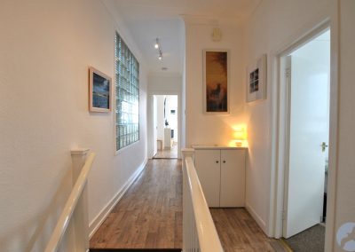 Long hallway with an open door on the right and a large window on the left.