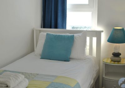Single bed with window behind.