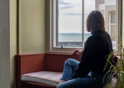 Someone sits on the window seat looking out towards the sea.