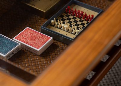 View through the top of a glass table to games beneath: two sets of playing cards and a small, peg board chess set.