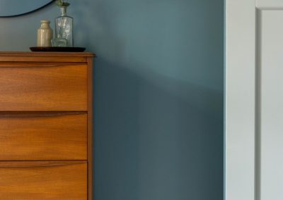 Close up of chest of drawers, mirror and bedroom door.